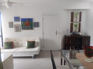 ein Wohnzimmer mit einem weißen Sofa und einem Glastisch in der Unterkunft APARTAMENTO RIVIERA DE SÃO LOURENÇO in Riviera de São Lourenço