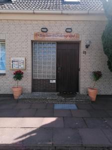 a front door of a building with two plants at Pension Weidengrund in Walsrode