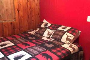 Ce lit se trouve dans une chambre dotée d'un mur rouge. dans l'établissement Royce’s Outpost Rustic cabin nearby trails, à Mio