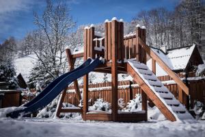 um parque infantil de madeira na neve com um escorrega em Chata Eva em Jezersko