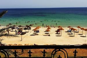 a beach with umbrellas and people in the ocean at Your ¥achting Home in Sousse