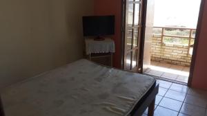 a bedroom with a bed and a tv and a window at Pousada Vila di Italia in Cidreira