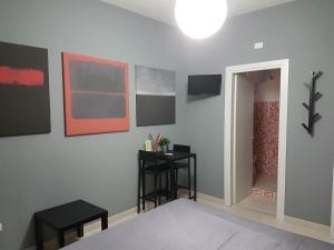 Zimmer mit einer Wand mit Gemälden und einem Tisch in der Unterkunft B&B Colors in Sellia Marina