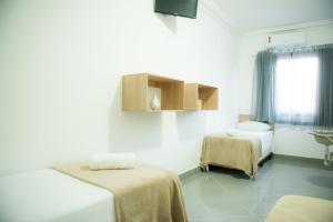 a hospital room with two beds and a window at Hotel Sabor e Fé in Aparecida