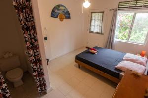 1 dormitorio con cama, aseo y ventana en Tavaetu Guesthouse - île de TUBUAI en Tubuai