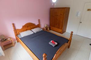 Tavaetu Guesthouse - île de TUBUAI في توبواي: غرفة نوم بسرير خشبي كبير مع بطانية زرقاء