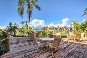 a wooden deck with tables and chairs on it at Resort-Style Condo with Pool 19 Miles to Fort Myers in Burnt Store Marina