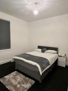 ein Schlafzimmer mit einem Bett in einem weißen Zimmer in der Unterkunft Home in Levenshulme, Manchester in Manchester
