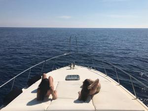 two women laying on the front of a boat in the ocean at Motor yacht 45' in Egina