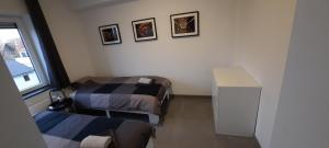 Una pequeña habitación con dos camas y una ventana. en Duplex appartement 4-6 pers La Traction Avant, en Ostende