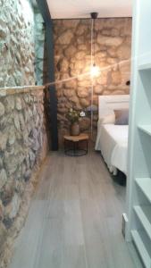 a bedroom with a bed and a stone wall at La Bodega in Andújar