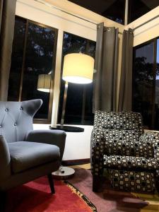 a living room with a chair and a lamp at Modern cabin nestled in mountain nature. Paradise! in Orosí