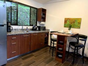 a kitchen with a sink and a table with stools at Modern cabin nestled in mountain nature. Paradise! in Orosí