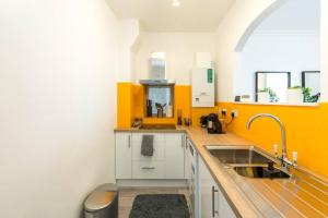 a kitchen with yellow and white walls and a sink at Superb flat close to super famous Portobello Road in London