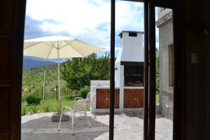 eine Terrasse mit einem Sonnenschirm, einem Tisch und einem Stuhl in der Unterkunft Aires del Alto - casas in Tafí del Valle