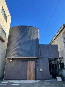 un edificio con techo negro y puerta de madera en Guest House Numazu Port - Vacation STAY 18050v en Numazu