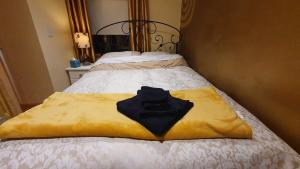 a black shirt on a yellow blanket on a bed at Forest Hills Lodge in Slane