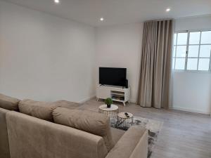 uma sala de estar com um sofá e uma televisão de ecrã plano em Apartment Til no Funchal