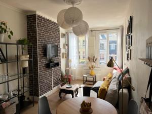 a living room with a table and a brick wall at Appartement Erik Satie in Honfleur
