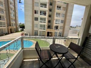 balcón con mesa, sillas y piscina en Departamento Full La Serena, en La Serena