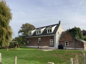 uma casa com um parque infantil em frente em Landhuis 'De Ontspanning' em Axel