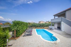 a swimming pool with lounge chairs next to a house at Vila Rozarija in Trogir