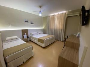 a hotel room with two beds and a television at JB Palace Hotel in Divinópolis