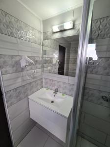 La salle de bains blanche est pourvue d'un lavabo et d'un miroir. dans l'établissement HOTEL CARMINA, à Rânca