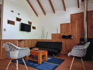 ein Wohnzimmer mit einem Sofa, Stühlen und einem Tisch in der Unterkunft La Casa del Árbol Villarrica Cabañas-Piscina-Tinajas in Villarrica