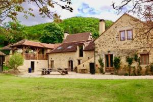 duży kamienny dom ze stołem piknikowym przed nim w obiekcie Les Paroules - Luxury Dordogne - Holiday Farmhouses. w mieście Saint-Cybranet