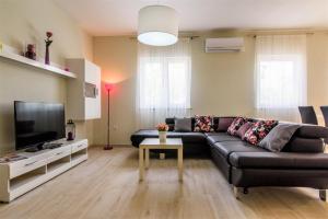 ein Wohnzimmer mit einem schwarzen Sofa und einem TV in der Unterkunft Vila Rozarija in Trogir