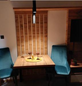 una mesa con dos copas de vino y dos sillas en Nela apartmani (u hotelu Djina), en Kopaonik