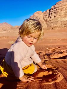 a young child sitting on the sand in the desert at wadi rum land mars in Wadi Rum