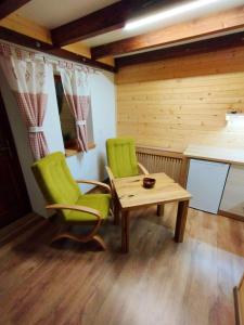 una habitación con 2 sillas verdes y una mesa en Apartmán Eliška Drevený raj, en Spišská Nová Ves