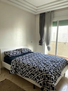 a bedroom with a bed with a black and white comforter at Joli logement in Casablanca