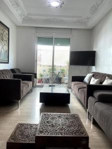 a living room with couches and a tv and a table at Joli logement in Casablanca