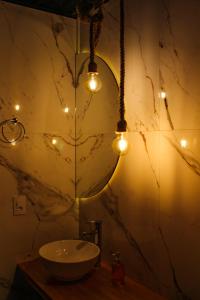 a bathroom with a sink and lights on the wall at Pousada Índios Coroados in Praia Grande