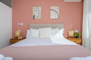 um quarto com uma cama branca e paredes cor-de-rosa em Juan Valera - Bellavista em Málaga