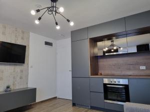 uma cozinha com fogão forno superior ao lado de uma televisão em M Lux Apartments em Banja Luka