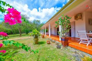 um alpendre de uma casa com uma cadeira e flores em AGREABLE VILLA DU DIAMANT em Le Diamant