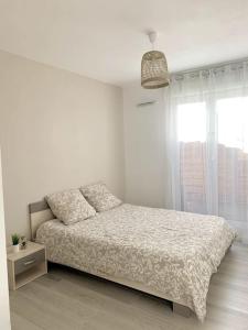 een witte slaapkamer met een bed en een raam bij Grand F3 à 30mn de Paris - Terrasse + Parking privé in Saint-Ouen-lʼAumône