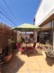 a patio with a table and chairs and a green umbrella at Hostal Geosol in Antofagasta