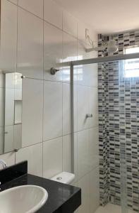 uma casa de banho com um lavatório e uma cabina de duche em vidro. em Apartamento inteiro 2 quartos Wi-Fi em Montes Claros