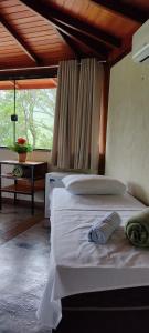 1 dormitorio con cama blanca y techo de madera en Pousada Jipe Canastra, en Capitólio