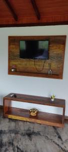 TV en la pared con estantería de madera en Pousada Jipe Canastra en Capitólio