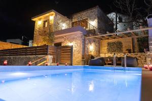 a swimming pool in front of a house at night at Lasithi Luxury Villa in Mésa Lasithákion