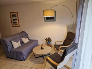 ein Wohnzimmer mit einem Sofa, 2 Stühlen und einem Tisch in der Unterkunft Appartement "La Mouette" 3 etoiles in Saint-Philibert