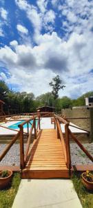 un paseo marítimo de madera que conduce a una piscina en un parque en Cabañas Samay en Casa Grande