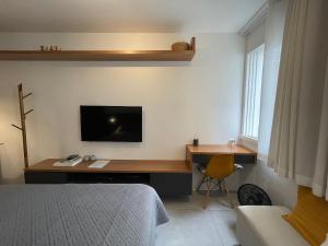 1 dormitorio con escritorio y TV en la pared en Conforto e praticidade próximo à Oscar Freire, en São Paulo