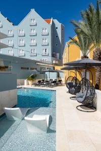 a pool with chairs and umbrellas next to a building at Harbor Hotel & Casino Curacao in Willemstad